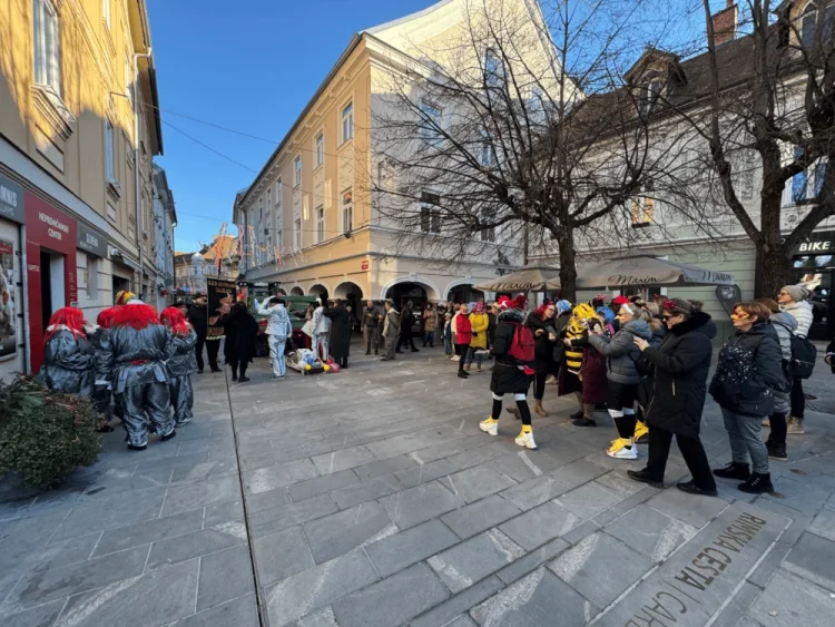 Ljudje in udeleženci v pustni maski se zberejo na ulici v Celju.